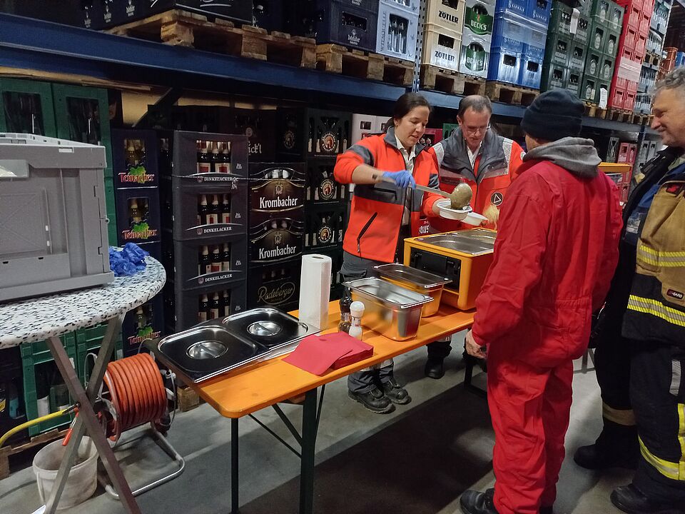 Einsatzkräfte des DRK Schwieberdingen geben warmes Essen an die Einsatzkräfte aus.
